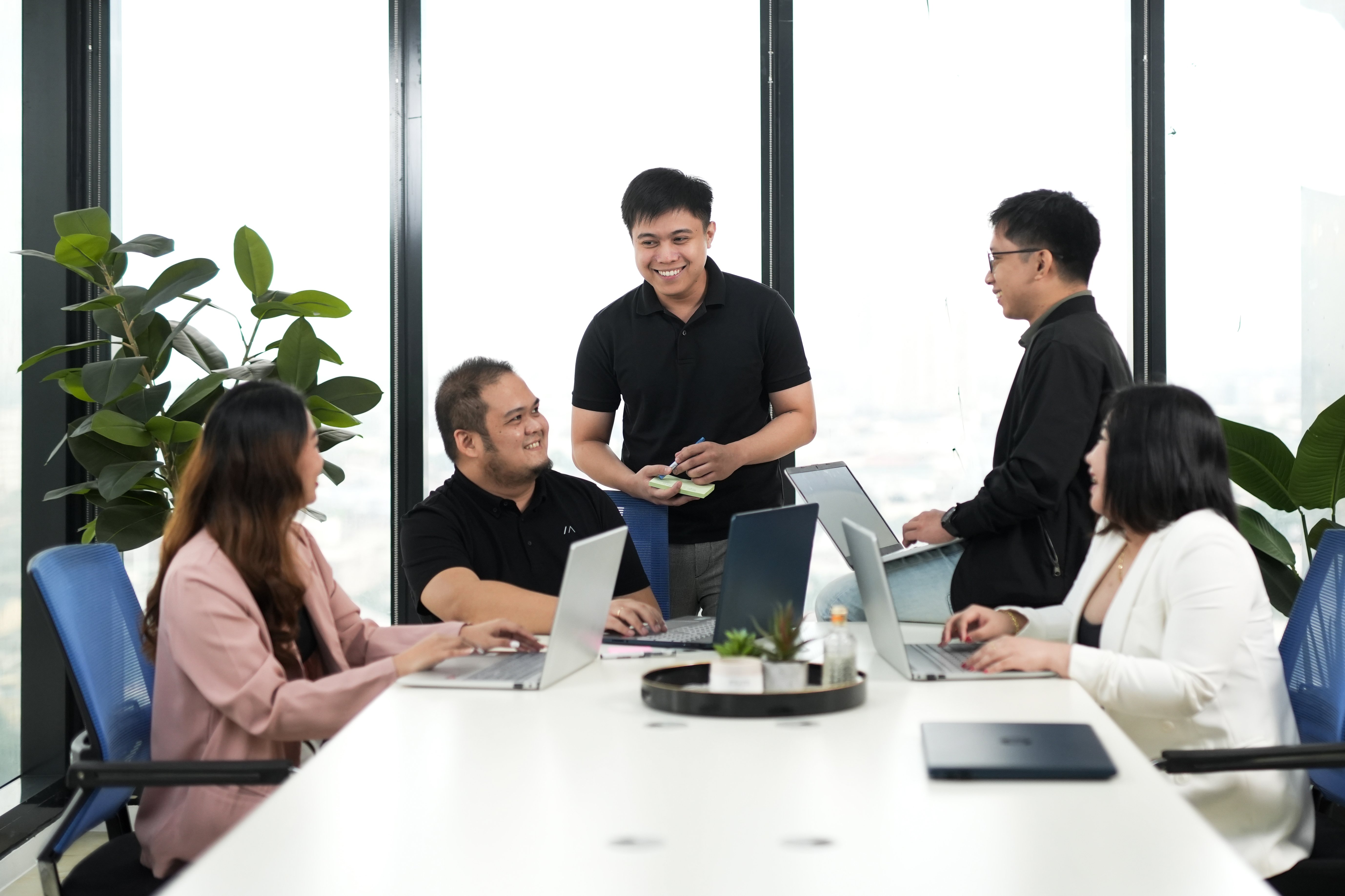 Team of professionals collaborating in a modern office meeting with laptops and discussion notes